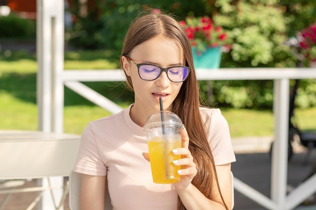 Garota adolescente de festa de verão com limonada refrescante no café de praia à mão