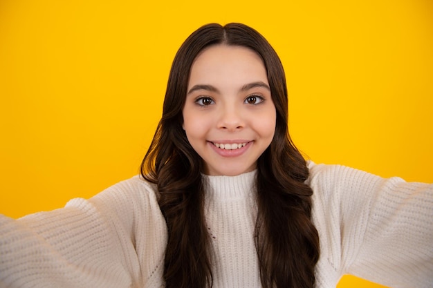 Garota adolescente engraçada fazendo selfie posando em fundo amarelo