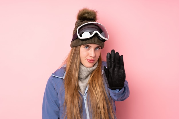 Garota adolescente esquiador com fundo de óculos de snowboard, fazendo o gesto de parada com a mão