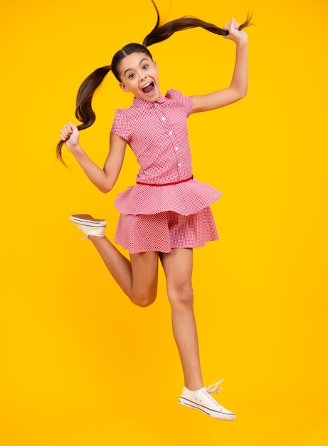 Garota adolescente feliz de comprimento total 12 13 14 anos pulando isolado no estúdio de fundo amarelo Salto engraçado Criança no vestido de movimento de verão