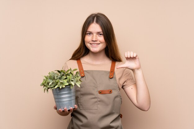 garota adolescente jardineiro segurando uma planta orgulhosa e satisfeita