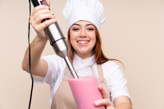 Foto garota adolescente ruiva usando liquidificador mão sobre parede isolada