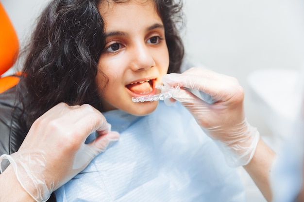 Garota adolescente segurando aparelho dentista coloca aparelho no atendimento odontológico da menina e conceito ortodôntico