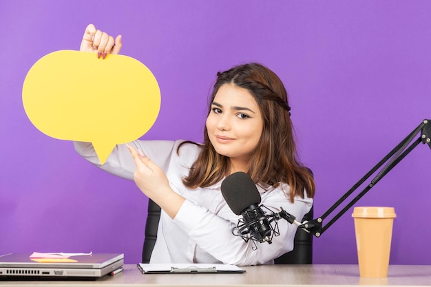 Garota adorável segurando bolha de ideia e sentado atrás da mesa Foto de alta qualidade