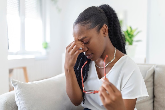 Garota africana de óculos esfrega os olhos, sofrendo de conceito de doenças oculares de olhos cansados