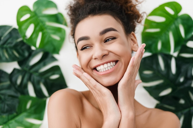 Foto garota afro-americana com pele perfeita sobre fundo com folhas tropicais