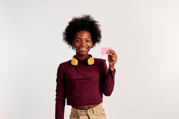 Foto garota afro-americana em poses de suéter marrom ao mostrar seu cartão de crédito.