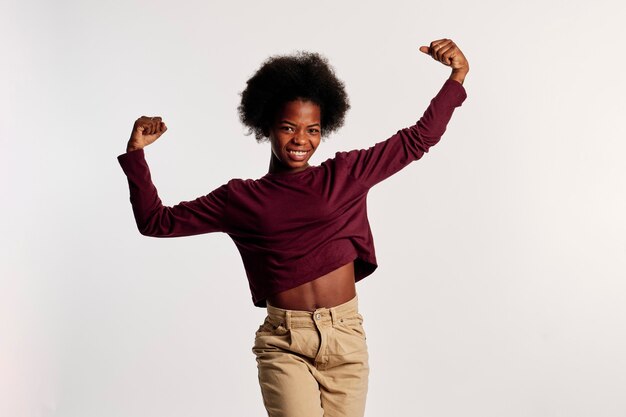 Foto garota afro-americana em poses de suéter marrom exibindo os braços