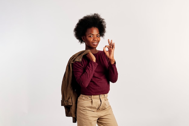 Garota afro-americana em poses de suéter marrom mostrando as mãos