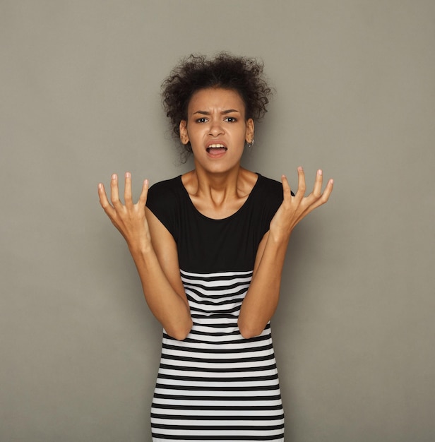 Garota afro-americana, gritando para a câmera. Jovem mulher emocional gesticulando bem para você, fundo escuro. Culpar, advertir, acusar conceito