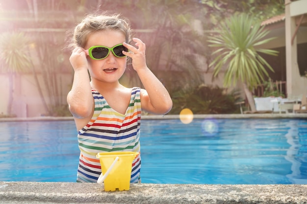 Garota ajustando os óculos de sol na piscina