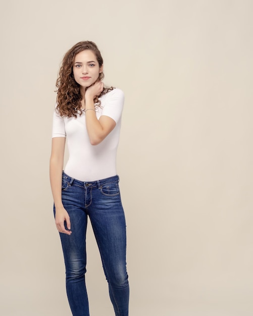 Garota alegre de corpo inteiro no estúdio White Tshirt jeans encaracolado