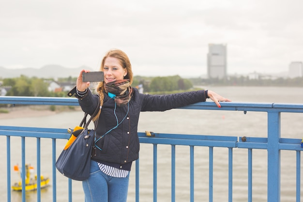 Garota alemã tomando selfie em Bonn com Rhein em fundo