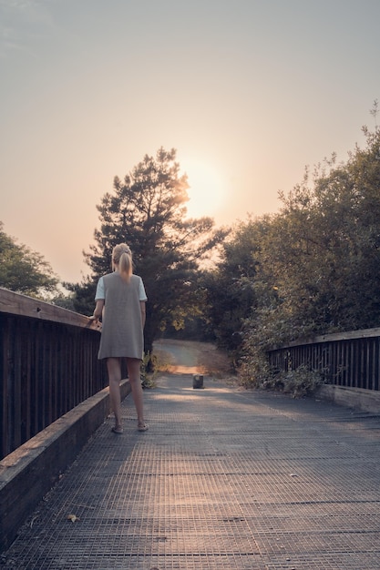 Garota andando na ponte de madeira Tranquilidade ao pôr do sol