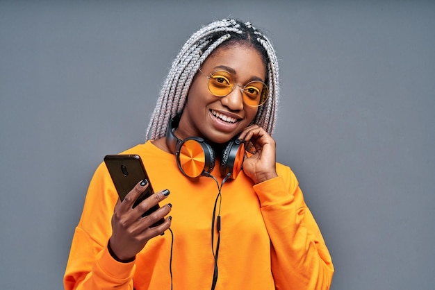 Garota animada com fones de ouvido coloridos posando com prazer e expressando emoções verdadeiras