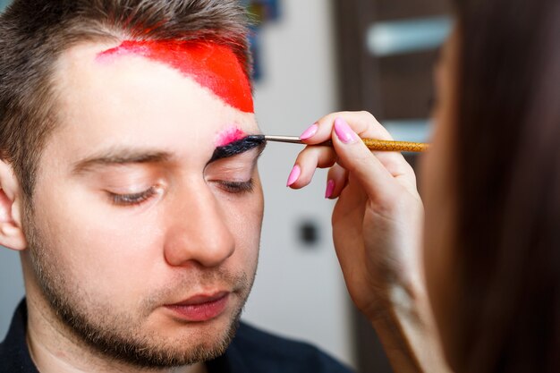 Garota artista pinta no rosto de um homem
