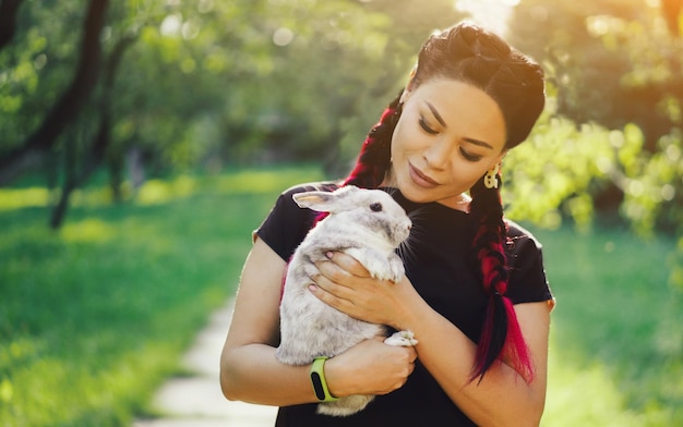 Garota asiática atraente segurando um coelho na natureza do verão