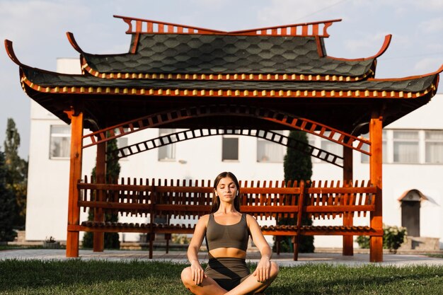 Garota asiática em forma está sentada em posição de lótus e meditando Meditação e relaxamento ao ar livre