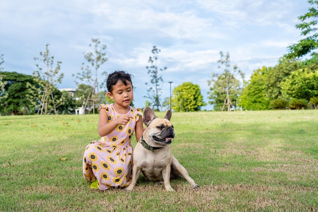 Garota ativa sentada com seu cachorro no campo.