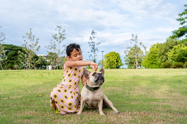 Garota ativa sentada com seu cachorro no campo.