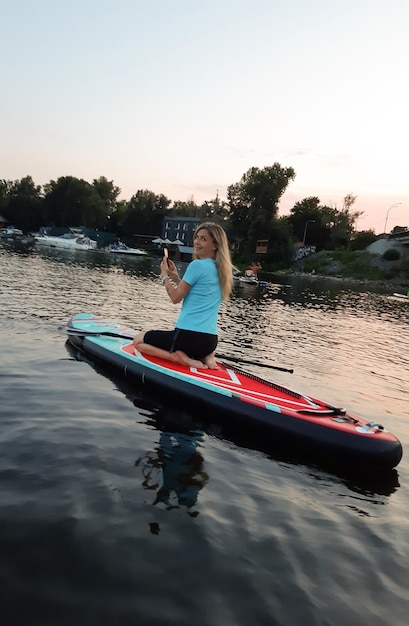 Garota atlética nada em um paddleboard para nadar SUP de joelhos e rema com um remo