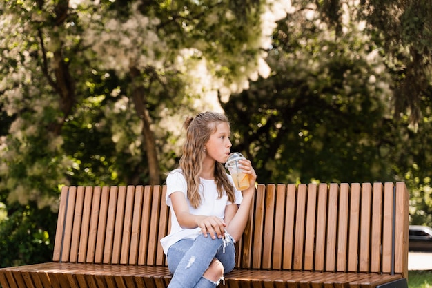 Garota atraente bebendo limonada de verão Coquetéis de verão Garota feliz segurando xícara com limonada laranja ao ar livre
