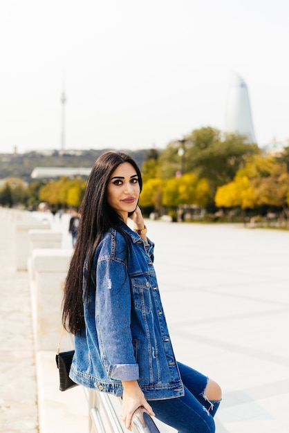 Garota atraente de cabelos negros posando no contexto da arquitetura moderna da cidade de Baku