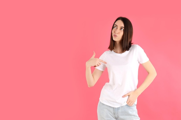 Garota atraente em camiseta branca em fundo rosa