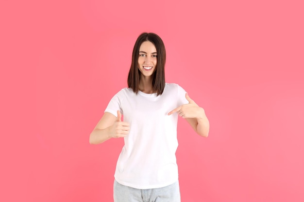 Garota atraente em camiseta branca em fundo rosa