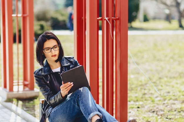 Garota atraente em copos com tablet no parque