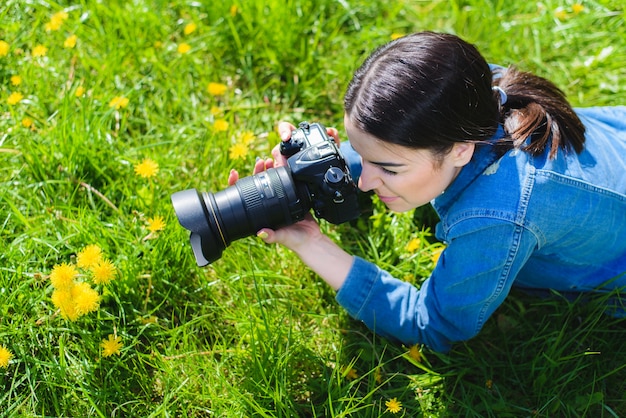 Garota atraente em um prado tira fotos de flores