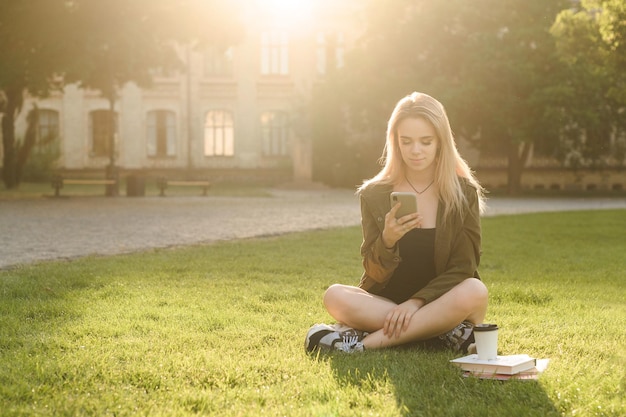 garota atraente inteligente usa um smartphone para uma pausa depois da aula