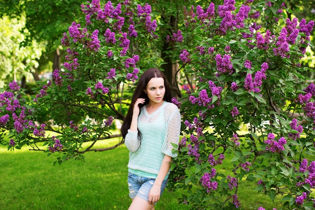 Garota atraente no parque contra uma árvore florida. retrato de mulher.