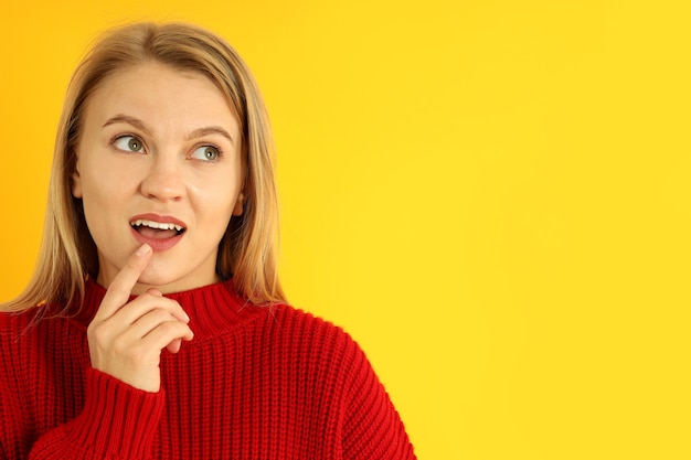 Garota atraente no suéter vermelho sobre fundo amarelo, espaço para texto.