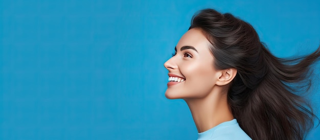 Garota atraente sorrindo em retrato de perfil com fundo azul e espaço de cópia