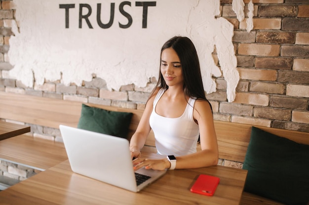 Garota atraente trabalhando no laptop no café linda garota usando computador para trabalhar garota bebendo