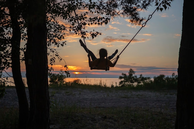 Garota balançando à beira-mar no pôr do sol de outono família caminhada na natureza, outono, viagens, estilo de vida ativo