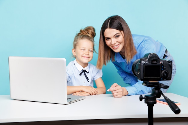 Garota blogueira gravando vlog na câmera, sentado com o laptop e a mãe, ajudando-a a ter uma boa aparência.