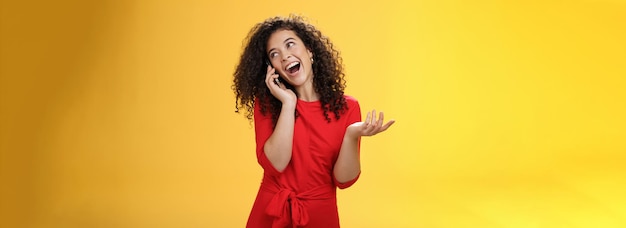 Foto garota boba de glamour falante com cabelos cacheados se divertindo se sentindo despreocupada e feliz falando no celular