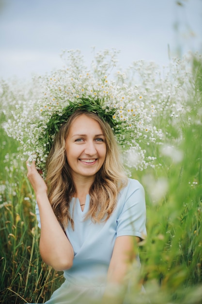 garota bonita em um campo de margaridas. garota com um chapéu de palha e um vestido azul. campo de camomila no verão