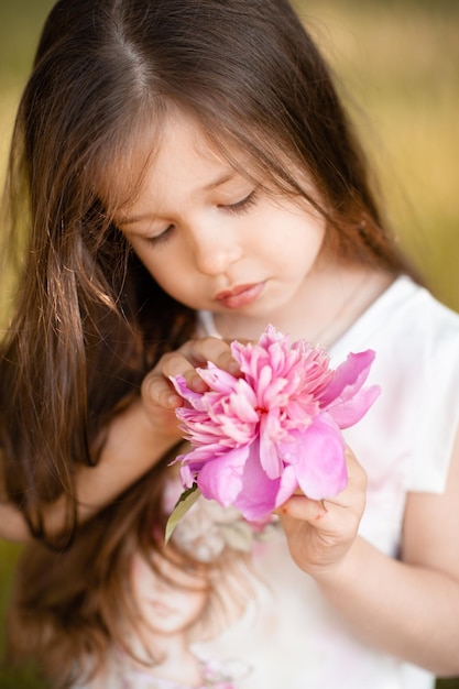 Garota bonita segurando flor de peônia rosa perto da primavera