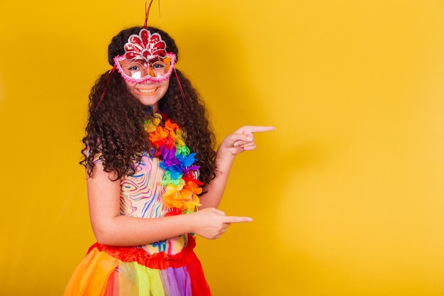 Garota brasileira caucasiana vestida para o carnaval de boas-vindas apontando para o lado negativo do espaço apresentando o produto