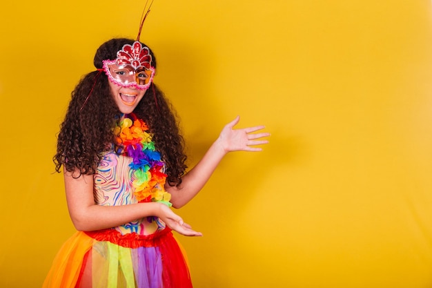 Garota brasileira caucasiana vestida para o carnaval de boas-vindas apontando para o lado negativo do espaço apresentando o produto