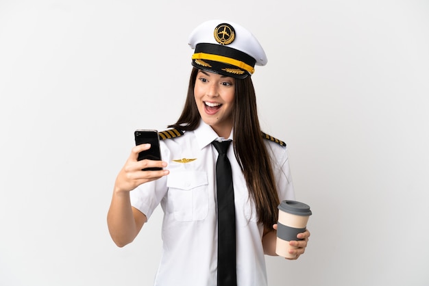 Garota brasileira Piloto de avião sobre fundo branco isolado segurando café para levar e um celular