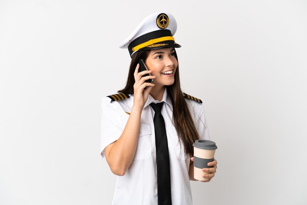 Garota brasileira Piloto de avião sobre fundo branco isolado segurando café para levar e um celular