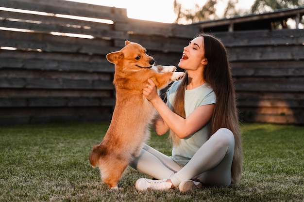 Garota brinca com cachorro corgi na grama e se diverte playful welsh corgi pembroke lifestyle com animal doméstico