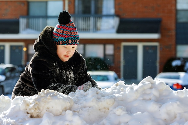 Garota brincando com neve perto da casa.