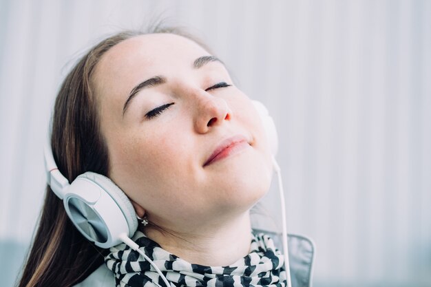 Garota caucasiana em fones de ouvido gosta de música na rua.