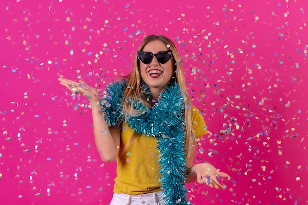 Garota caucasiana festejando na discoteca rindo jogando confete isolado em um fundo rosa usando óculos escuros