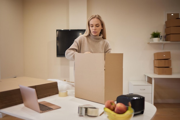 Garota caucasiana gravando caixas para se mudar para um novo apartamento